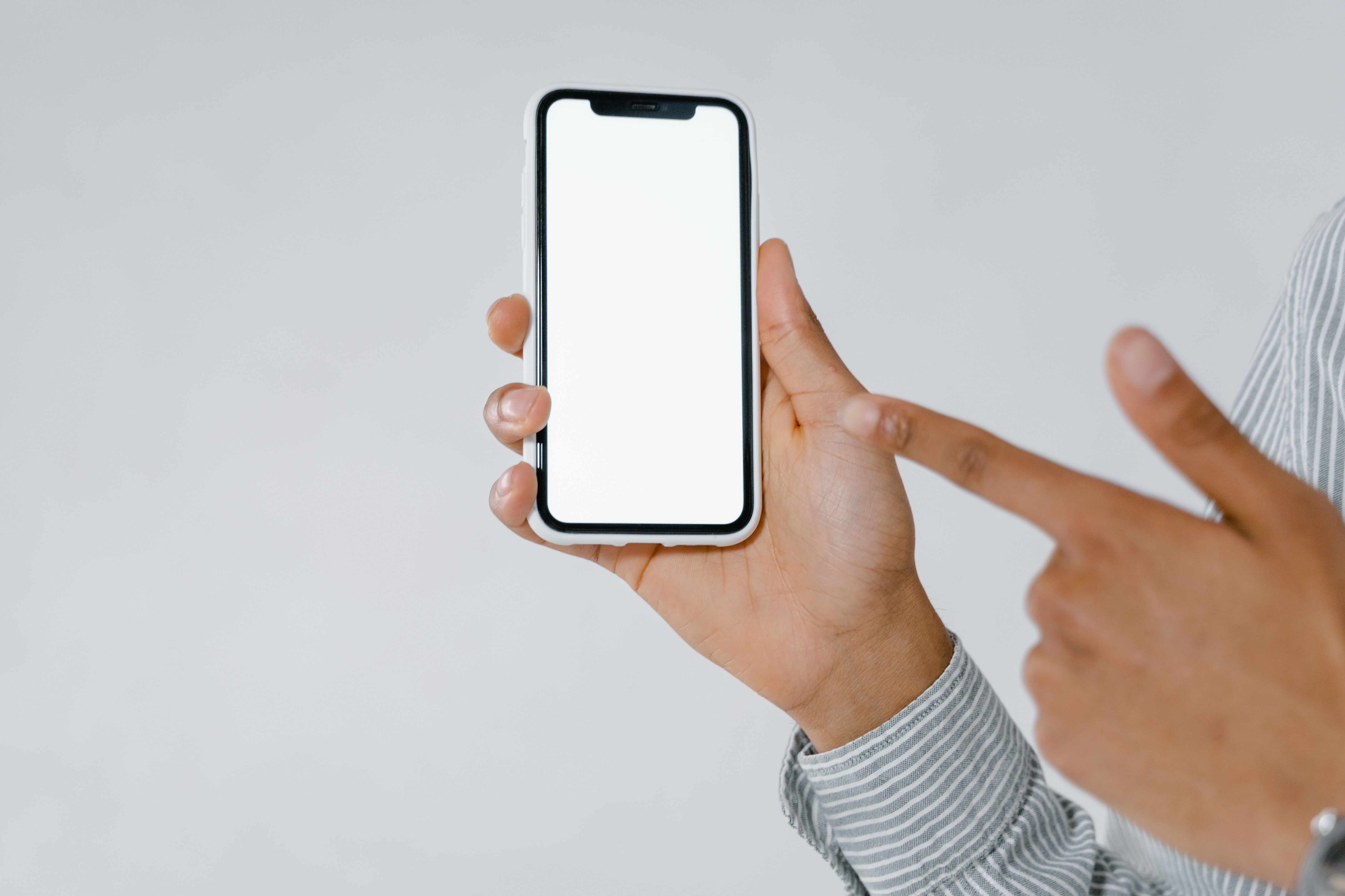 Person pointing at a smartphone with a blank screen, useful for illustrating a mobile landing-page call to action.