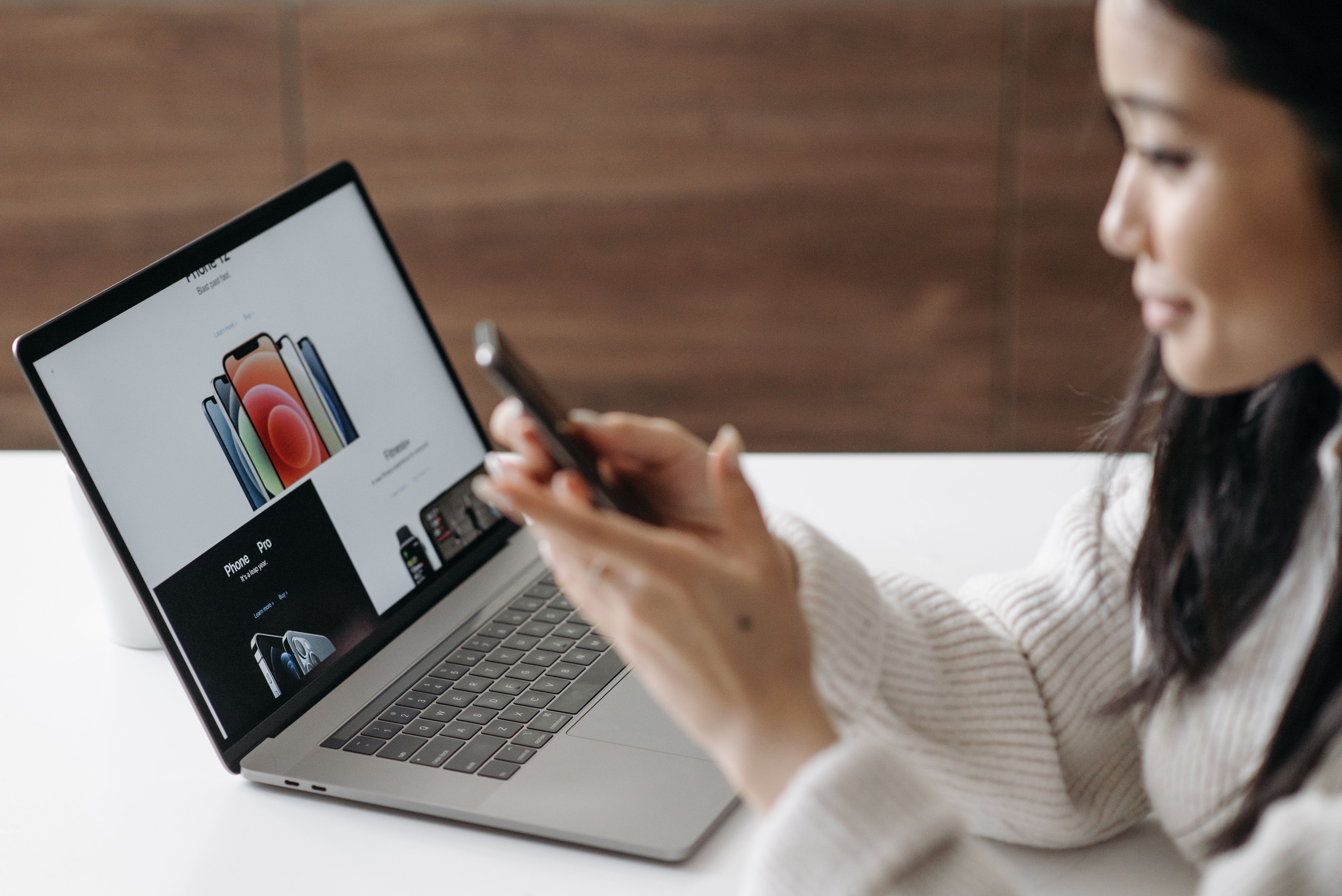 Woman shopping online with a laptop and smartphone, representing a focused landing-page conversion experience.