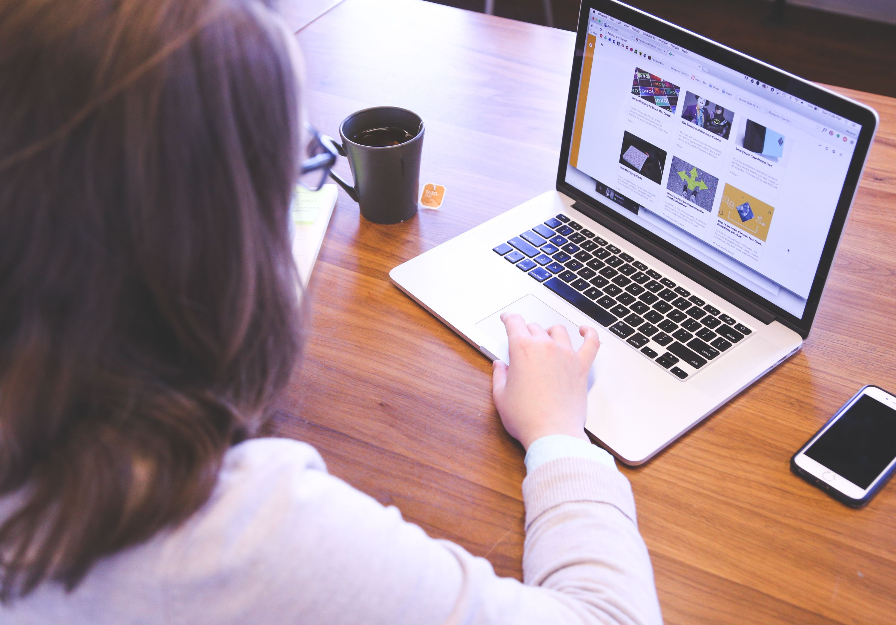 Person browsing the web on a laptop beside a smartphone, illustrating the transition from a social ad to a landing page.